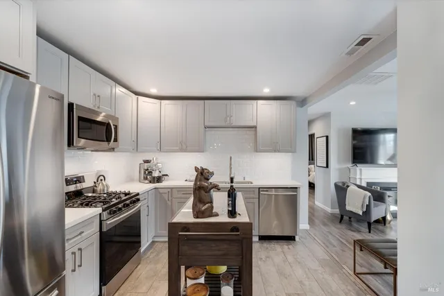 a kitchen with kitchen island white cabinets and stainless steel appliances