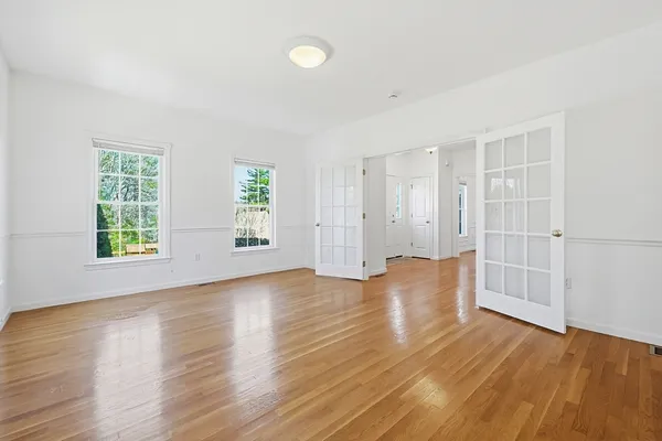 an empty room with wooden floor and windows