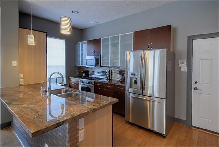 1414 Emancipation Avenue, Unit A Houston, TX 77003 - Photo 6 of 22 a kitchen with stainless steel appliances granite countertop a refrigerator a stove and a sink with wooden floor