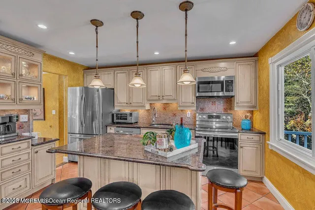 a kitchen with stainless steel appliances granite countertop a stove a refrigerator a oven a sink with a dining table and chairs