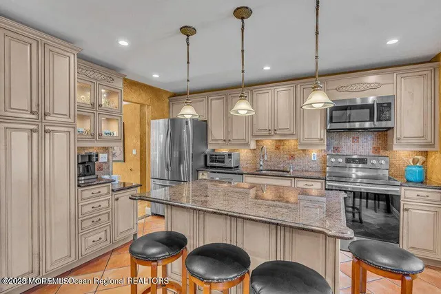 a kitchen with stainless steel appliances granite countertop a sink a stove a refrigerator cabinets and chairs