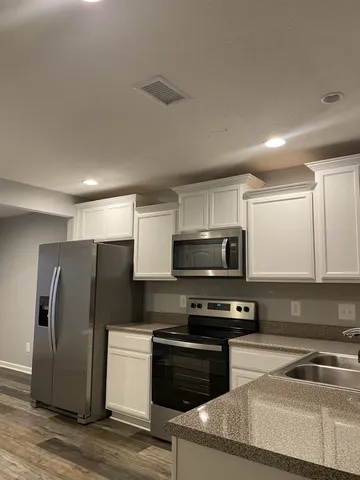 a kitchen with granite countertop a refrigerator and a stove top oven