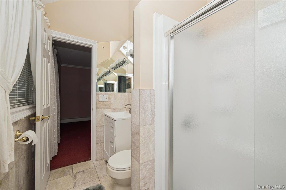 346 Ridgefield Road Hauppauge, NY 11788 - Photo 11 of 45 Bathroom with vanity, light tile patterned floors, a stall shower, and tile walls