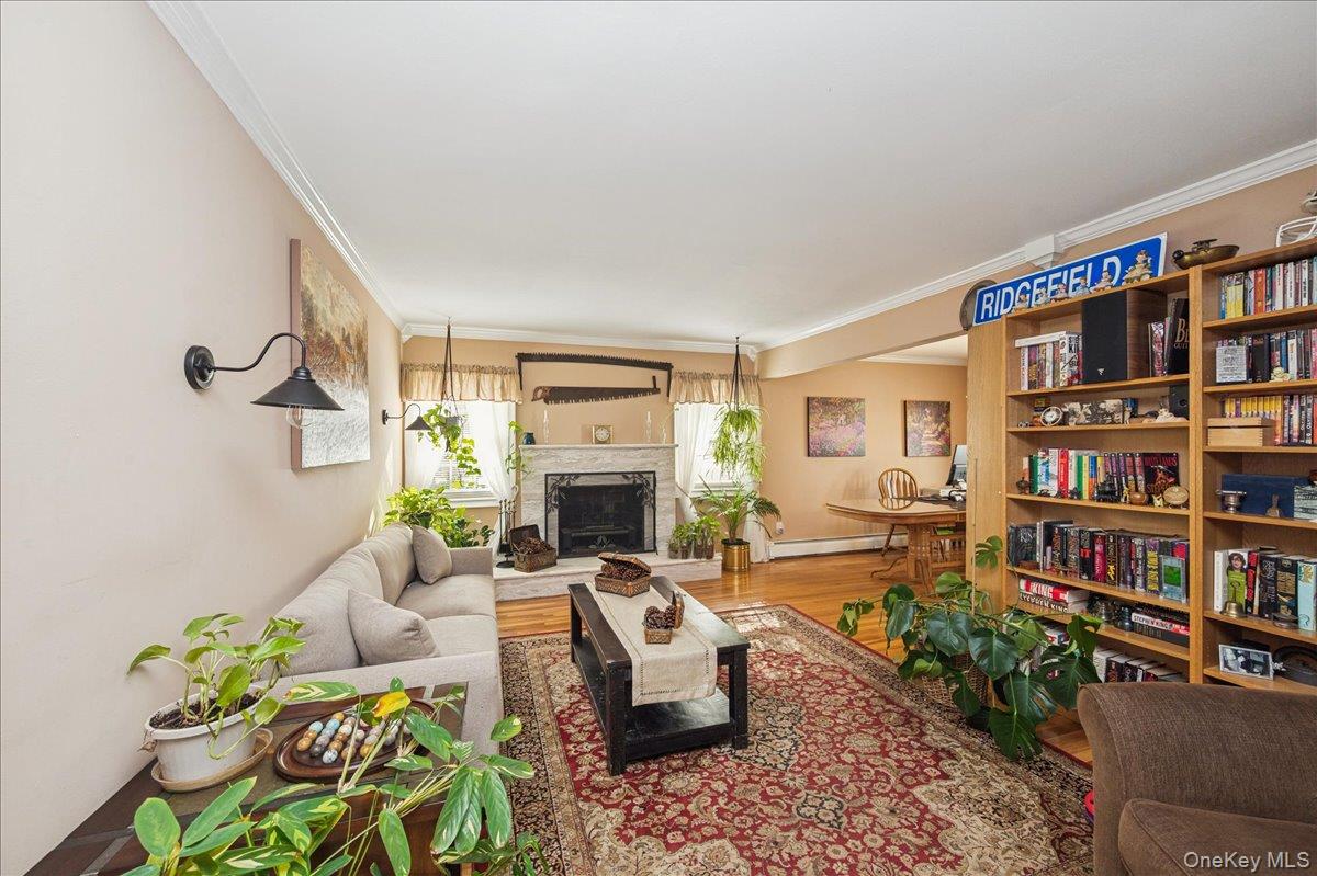 346 Ridgefield Road Hauppauge, NY 11788 - Photo 13 of 45 Living room featuring crown molding, wood finished floors, a fireplace with raised hearth, and a baseboard heating unit