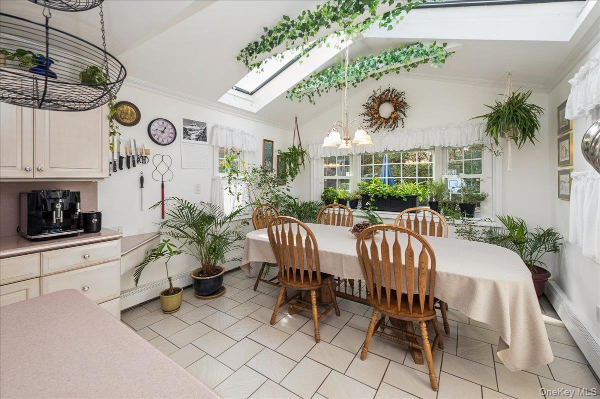 346 Ridgefield Road Hauppauge, NY 11788 - Photo 24 of 45 Dining space with a skylight, vaulted ceiling, a chandelier, ornamental molding, and light tile patterned flooring