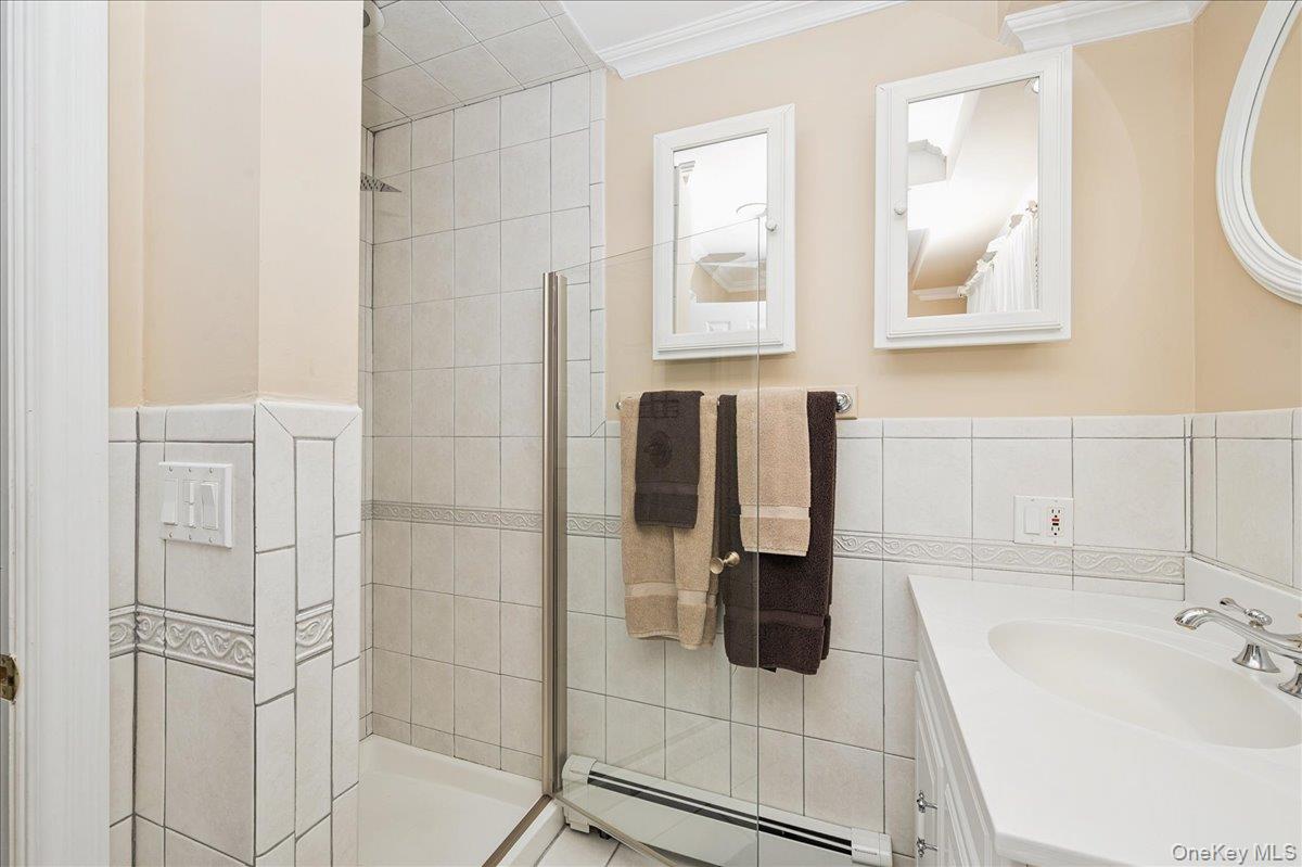 346 Ridgefield Road Hauppauge, NY 11788 - Photo 30 of 45 Bathroom featuring vanity, baseboard heating, tile walls, a stall shower, and crown molding