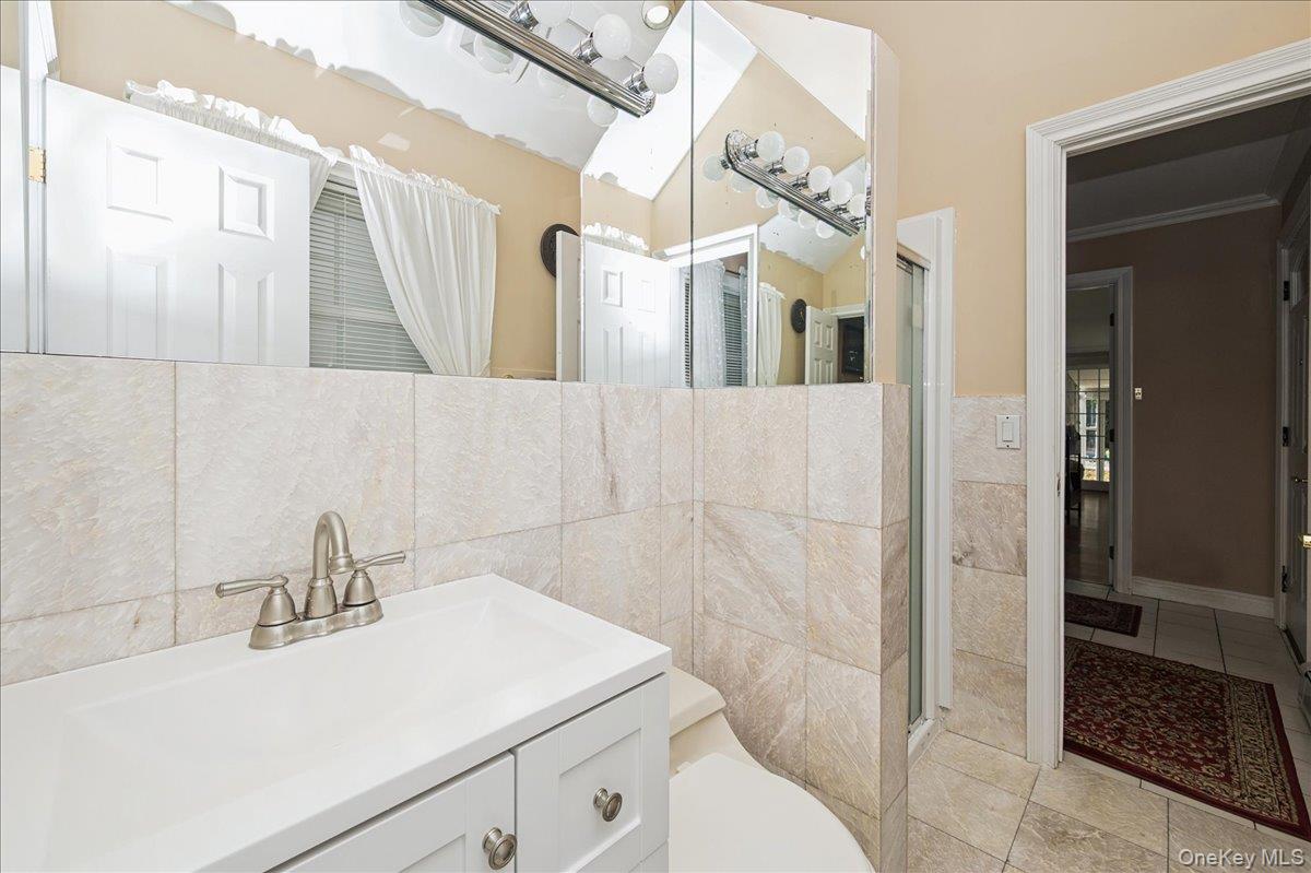 346 Ridgefield Road Hauppauge, NY 11788 - Photo 7 of 45 Bathroom featuring a shower stall, vanity, tile walls, light tile patterned floors, and ornamental molding