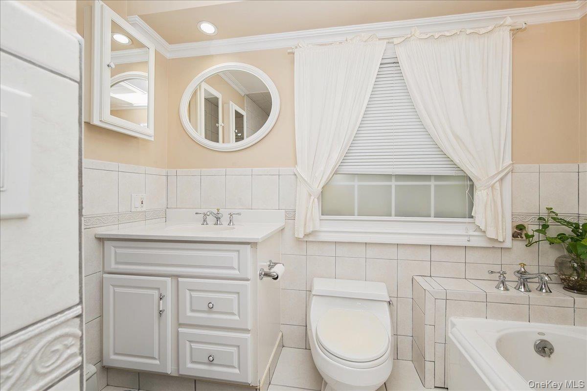 346 Ridgefield Road Hauppauge, NY 11788 - Photo 10 of 45 Full bathroom featuring tile walls, vanity, ornamental molding, a garden tub, and tile patterned floors