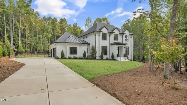 a view of a white house next to a yard with big trees