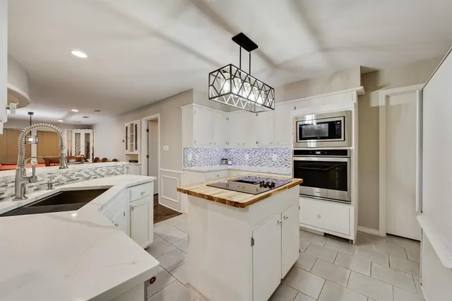a kitchen that has a lot of white cabinets and stainless steel appliances