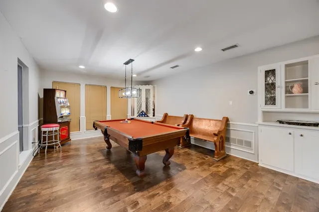 a room with furniture pool table flat screen tv and windows