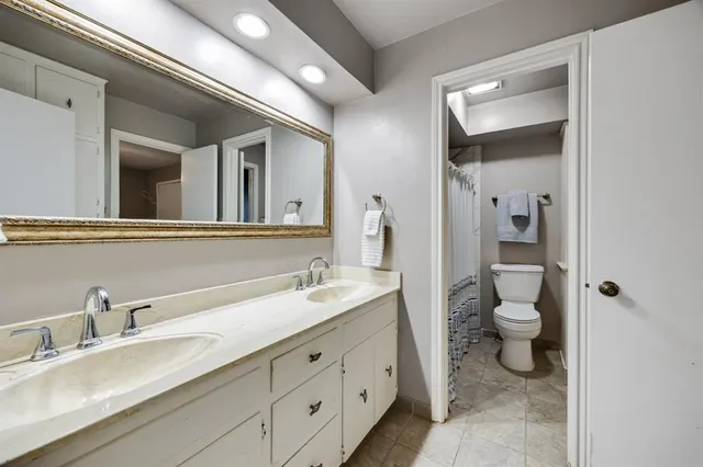 a bathroom with a double vanity sink toilet and a mirror