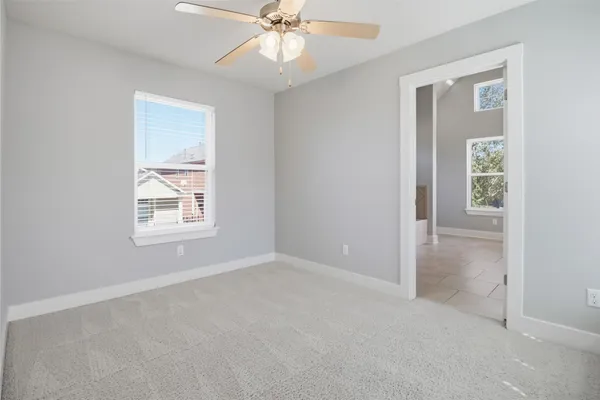 an empty room with windows and fan