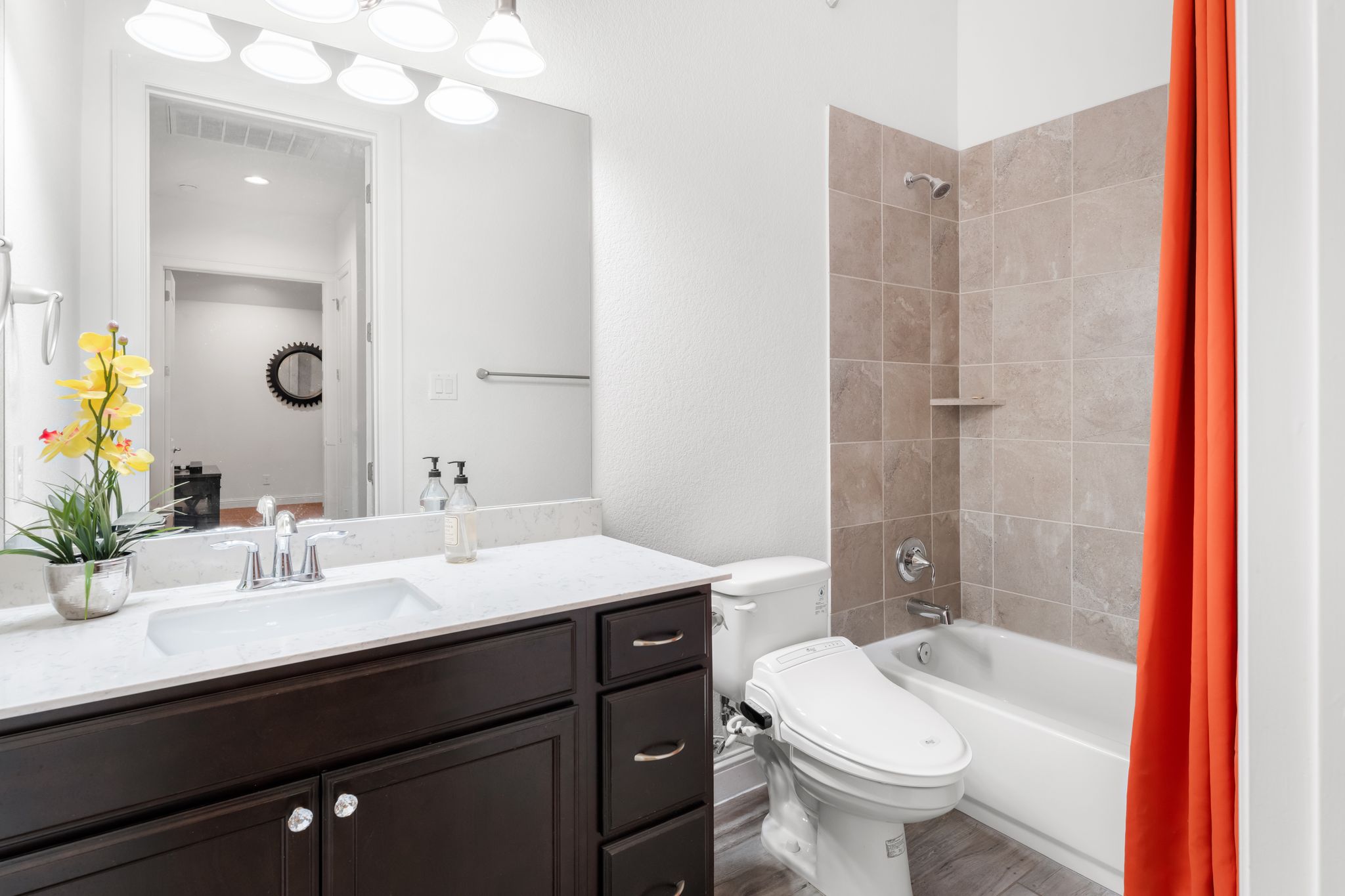 140 Waterloo Cove Georgetown, TX 78628 - Photo 6 of 40 A well-appointed bathroom features a dark wood vanity with white stone counters and a tiled shower-bathtub combination and bidet!