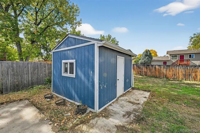 a backyard of a house with large trees and wooden fence