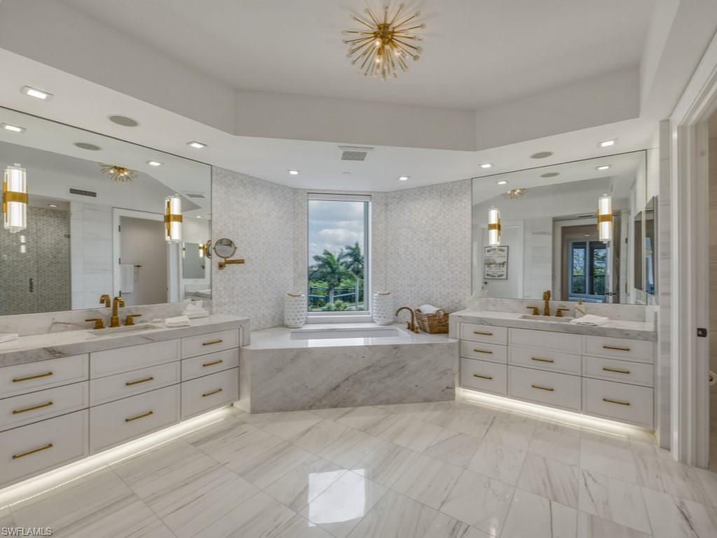 8787 Bay Colony Drive, Unit 306 Naples, FL 34108 - Photo 21 of 40 a large bathroom with a granite countertop double vanity sink a mirror and a bathtub