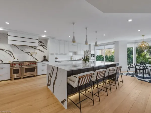 a kitchen with stainless steel appliances granite countertop a table chairs sink and cabinets