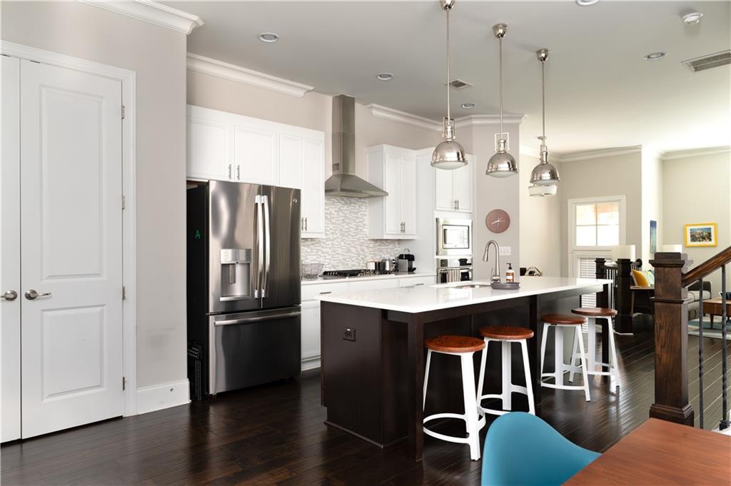 1940 Townsend Court, Unit 15 Atlanta, GA 30329 - Photo 8 of 36 a kitchen with stainless steel appliances granite countertop a refrigerator a sink dishwasher a stove and white countertops with wooden floor