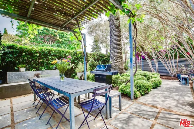 a patio with table and chairs and potted plants
