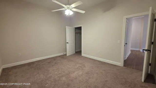 an empty room with closet and a chandelier fan