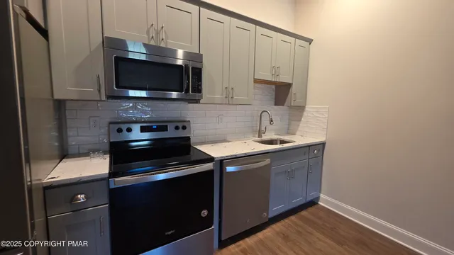 a kitchen with stainless steel appliances a stove microwave and sink