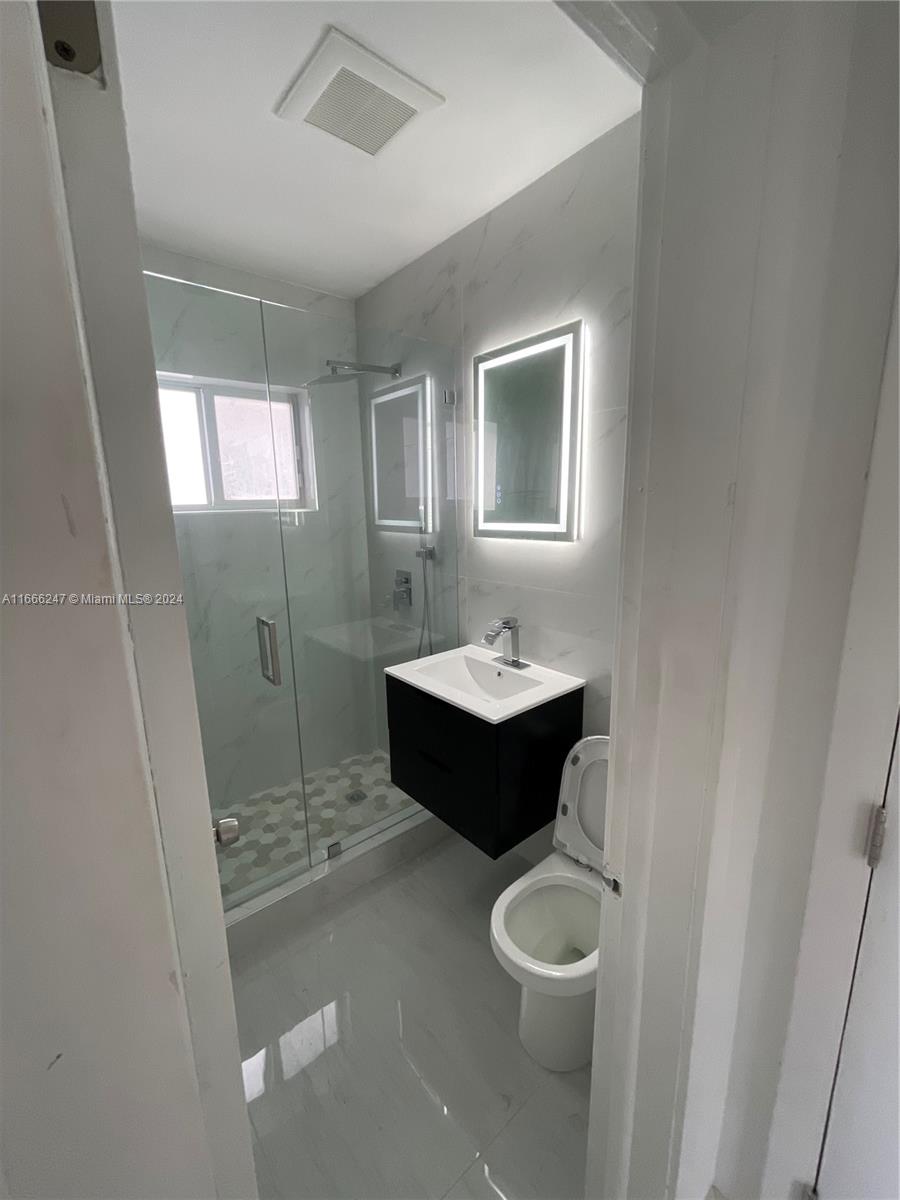 3112 Southwest 16th Street, Unit 3110 Miami, FL 33145 - Photo 12 of 19 a bathroom with a toilet a sink a mirror and a tub