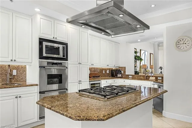 a kitchen with kitchen island granite countertop a sink cabinets and stainless steel appliances