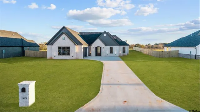 a view of a house with a big yard potted plants and large tree
