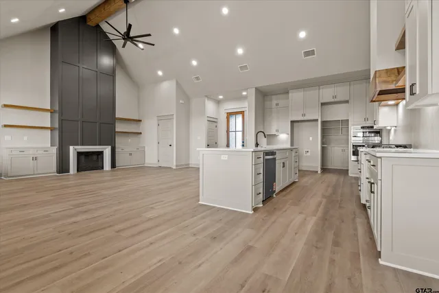 a open kitchen with kitchen island a stove a sink dishwasher and a refrigerator with wooden floor