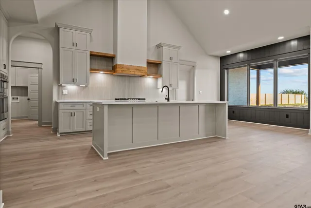 a kitchen with stainless steel appliances granite countertop a stove top oven a sink dishwasher and a refrigerator with wooden floor