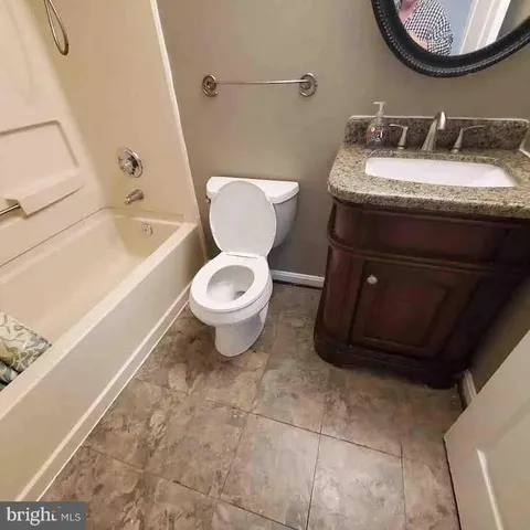 a bathroom with a granite countertop toilet sink and mirror