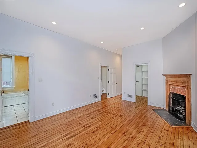a big room with wooden floor and a fireplace