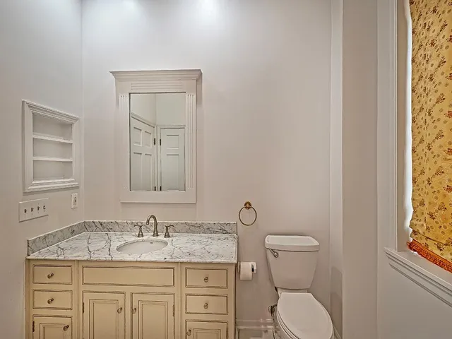 a bathroom with a granite countertop toilet sink and mirror