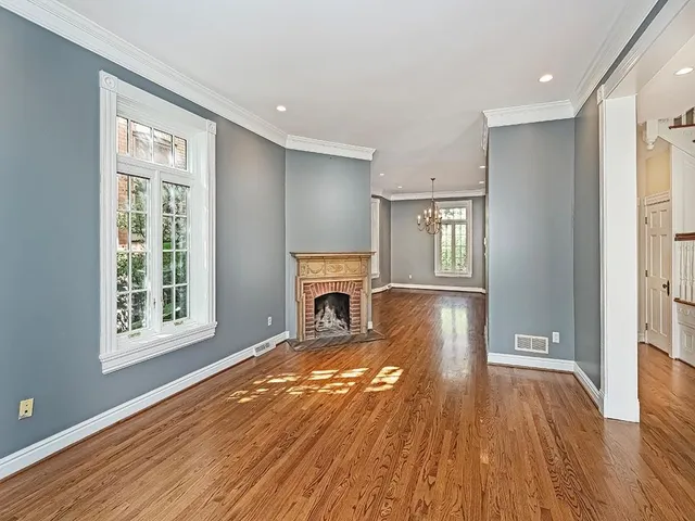 a view of a livingroom with wooden floor a fireplace and windows