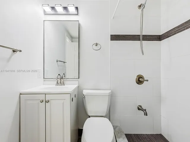a bathroom with a toilet a sink a mirror and shower