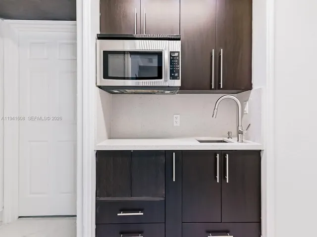 a view of microwave a sink and cabinets