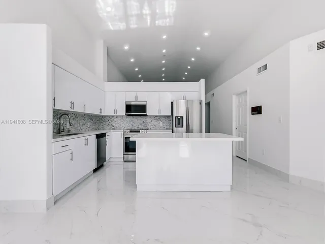 a large white kitchen with a white countertops and cabinets