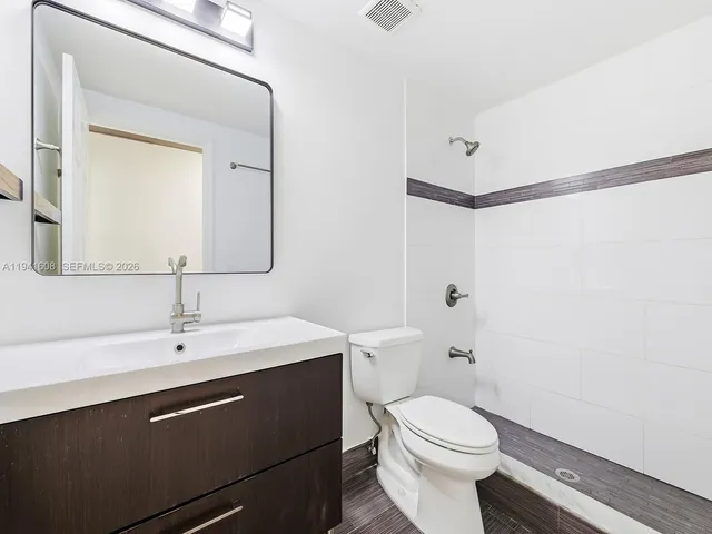 a bathroom with a sink a toilet a mirror and shower