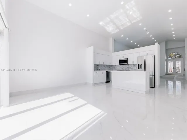 a large white kitchen with a refrigerator a stove a sink and a cabinets