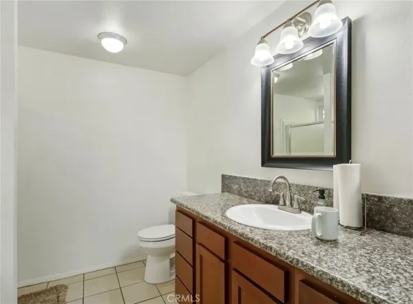 a bathroom with a granite countertop sink a toilet and a mirror