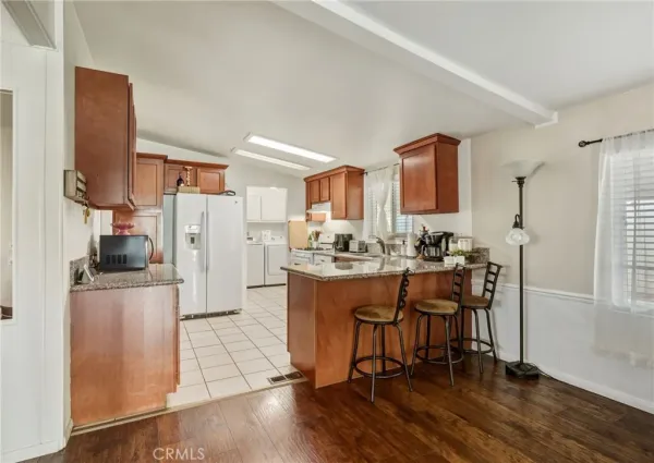 a kitchen with stainless steel appliances a refrigerator a stove a sink dishwasher and white cabinets with wooden floor