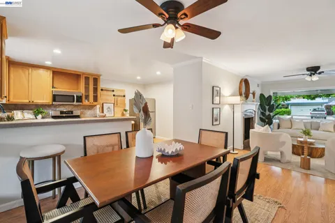 a dining room with stainless steel appliances kitchen island granite countertop a dining table chairs and a refrigerator