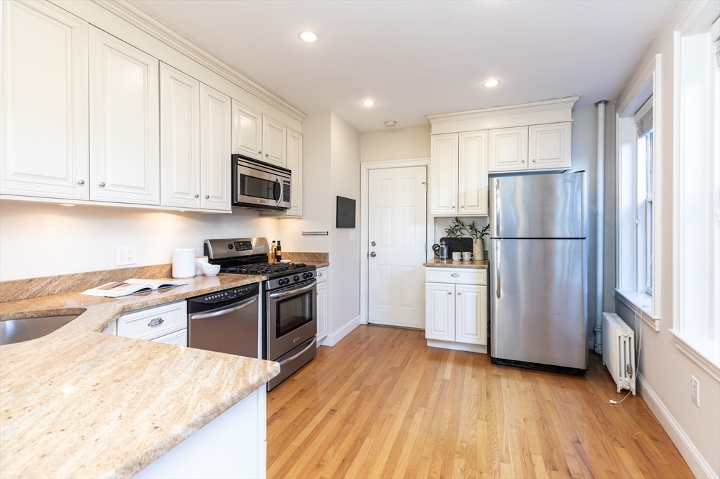 76 West Cedar Street, Unit 4F Boston, MA 02114 - Photo 6 of 22 a kitchen with a refrigerator stove and wooden cabinets