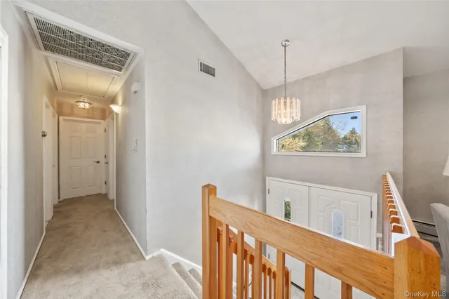 a view of a hallway with windows and chandelier