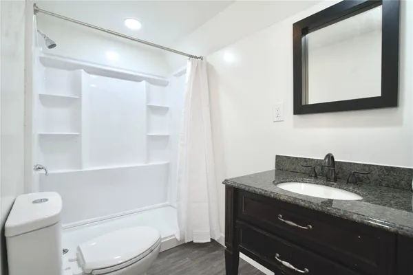a bathroom with a granite countertop toilet sink and mirror