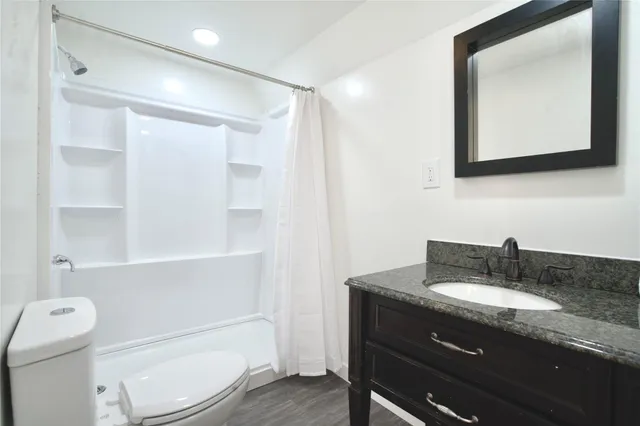 a bathroom with a granite countertop toilet sink and mirror