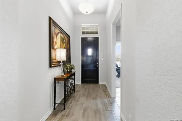 a view of a hallway to a livingroom with wooden floor and a window