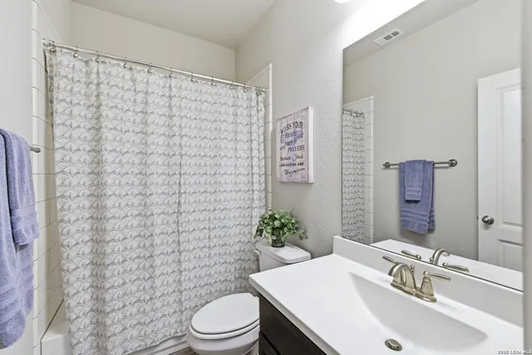a bathroom with a sink a toilet and shower curtain