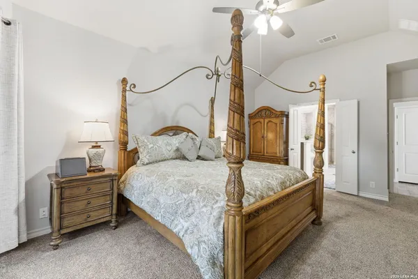 a spacious bedroom with a bed a chandelier and dresser