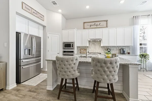 a kitchen with stainless steel appliances granite countertop a refrigerator and a stove top oven